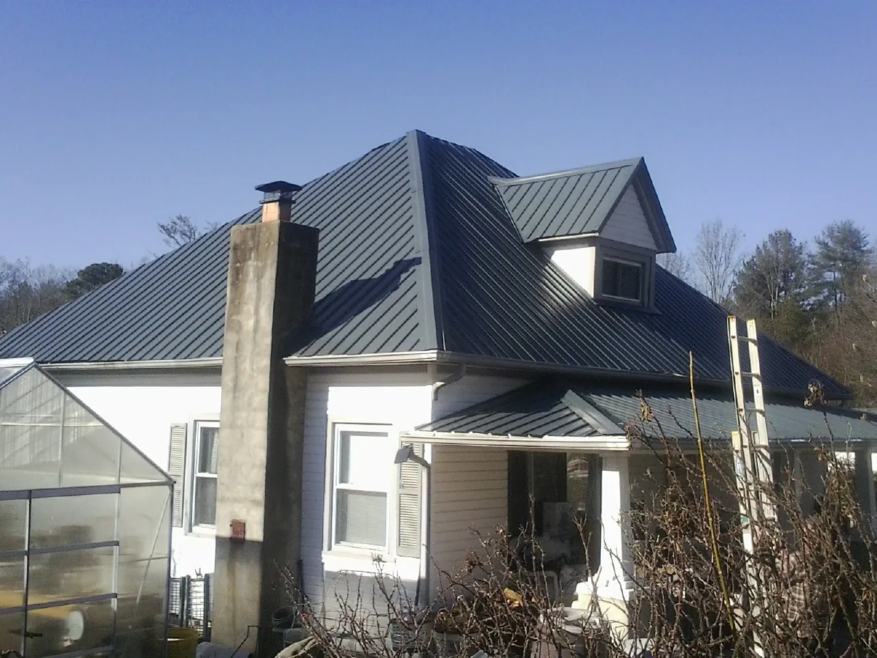 Dark blue standing seam metal roof on a white farmhouse with dormer — Slate & Tile Roof Repair by Roofing Brothers in Munds Park