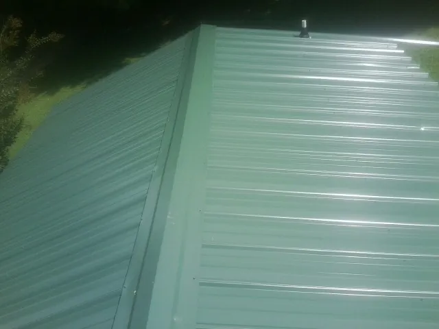 New green metal panels meeting at the ridge of a roof — Flat Roof Repair work by our crew in Munds Park