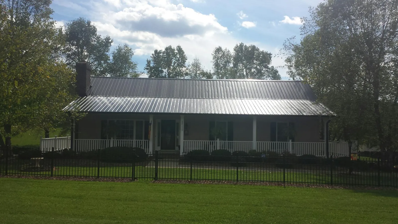 Gray metal roof on a brick ranch with a full width front porch — Gutter Guard Installation work by our crew in Munds Park