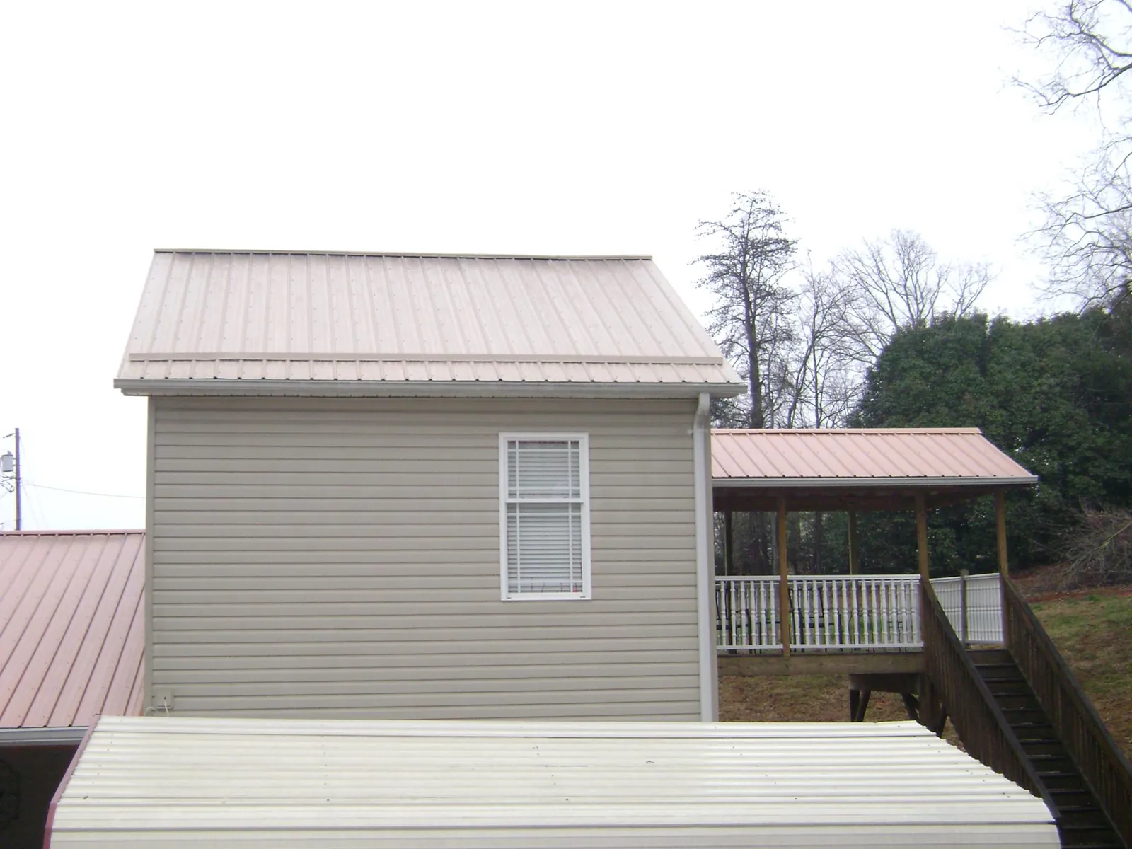 Tan metal roofs on a two story addition and attached porch, from a Roof Replacement job in Munds Park