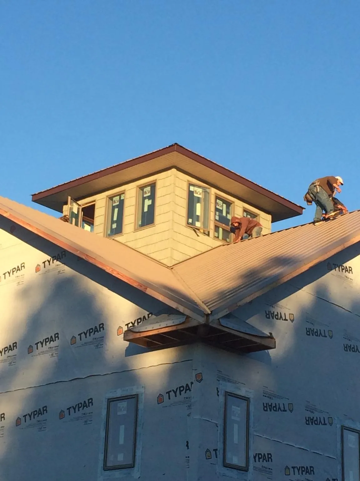 Roofers working around a rooftop cupola on a new metal roof at sunset — Roof Waterproofing in Munds Park by Roofing Brothers